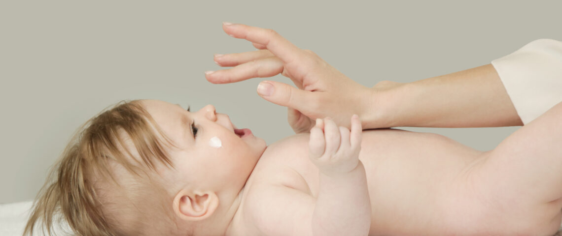 Baby handling: Woman applying moisturizing cream on her baby's face Baby handling: Woman applying moisturizing cream on her baby's face